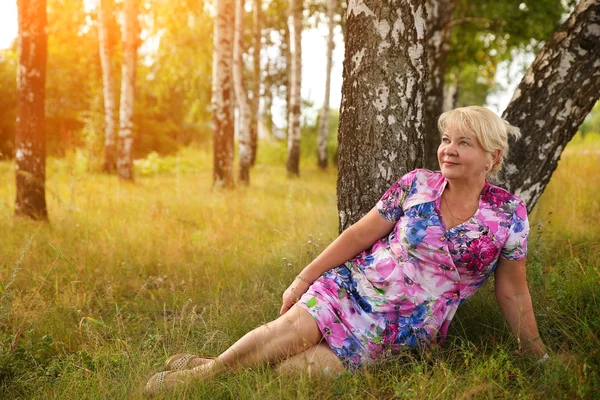 Leende senior kvinna sitter i parken — Stockfoto