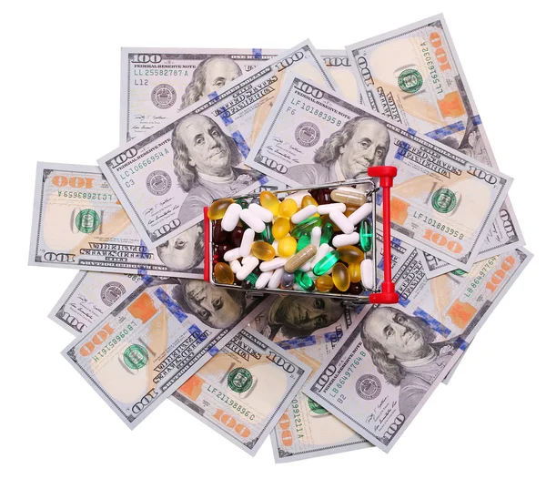 Shopping cart full with pills and capsules over dollar bills — Stock Photo, Image