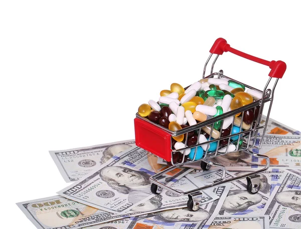 Carro de compras lleno de pastillas sobre billetes de dólar, aislado —  Fotos de Stock