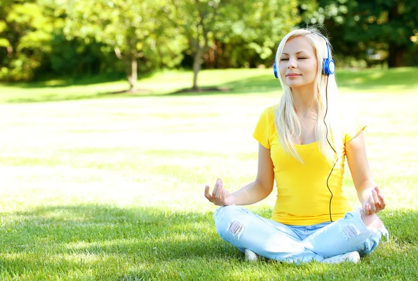 Mulher loira com fone de ouvido meditando ao ar livre. Estudante menina — Fotografia de Stock