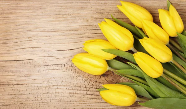 Gelbe Tulpen auf einem hölzernen Hintergrund — Stockfoto