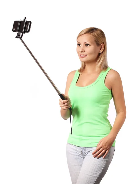 Mujer joven tomando foto selfie con palo aislado en blanco — Foto de Stock