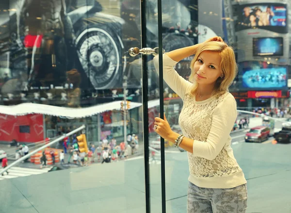 Meisje poseren in de buurt van raam met het uitzicht op Time Square — Stockfoto