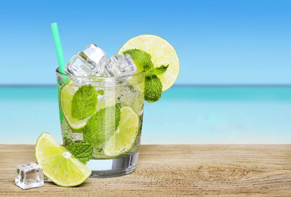 Coquetel de mojito com limão sobre fundo de praia tropical — Fotografia de Stock