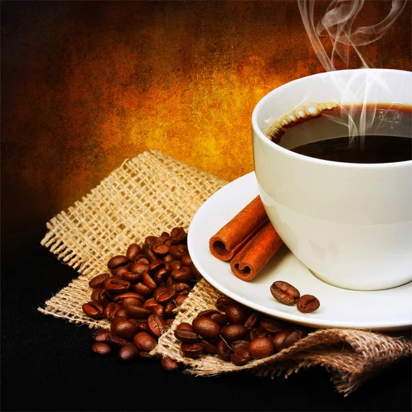 Coffee cup with saucer and coffee beans on burlap over dark — Stock Photo, Image