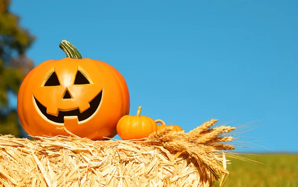 Halloween dýně, legrační Jack O'Lantern na balíku slámy nad Sky. — Stock fotografie