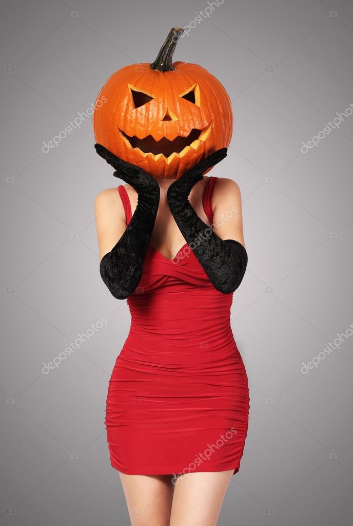 Halloween. Sexy lady in red with big pumpkin on head. Stock Photo by