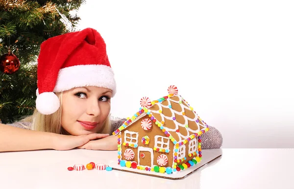 Happy Girl making Gingerbread House. Young Woman with Santa Hat — Stock Photo, Image
