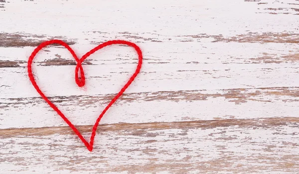 Den svatého Valentýna. Červené srdce vlákna ve tvaru na dřevěné pozadí — Stock fotografie