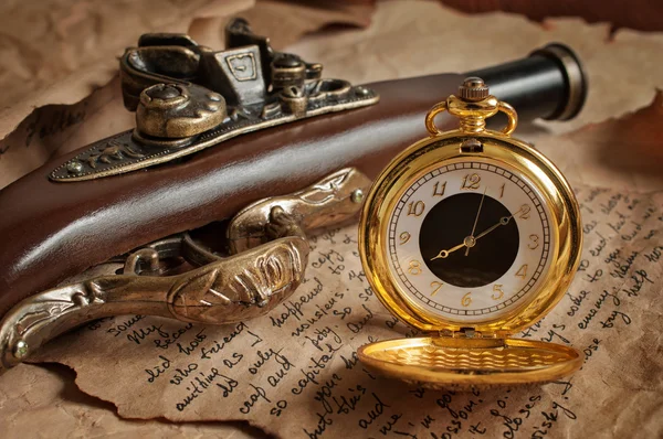 Retro zlaté kapesní hodinky a starožitné pistole — Stock fotografie