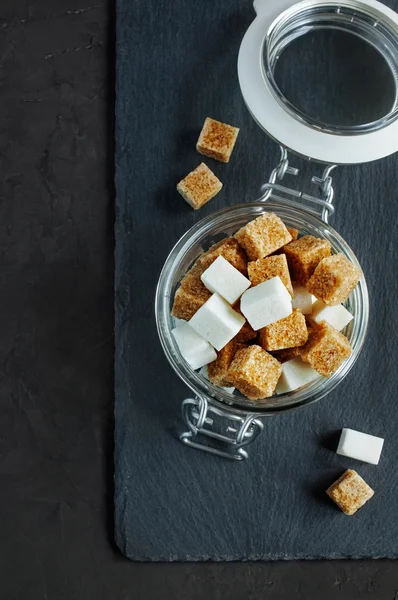 Cubos de azúcar blanco y moreno en un frasco de vidrio — Foto de Stock