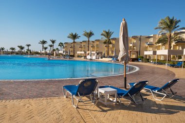 Lüks otelde palmiye ağaçları olan güzel bir yüzme havuzu. Mısır tatil köyünde güneşli bir gün