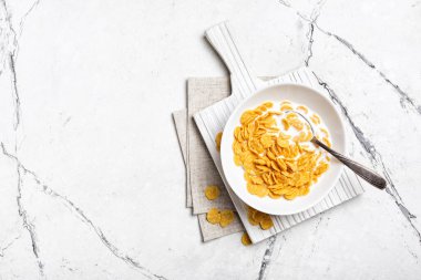 Kahvaltıda mısır gevreği ve sütle birlikte beyaz mermer arka planda fotokopi alanı olan kâse manzarası.