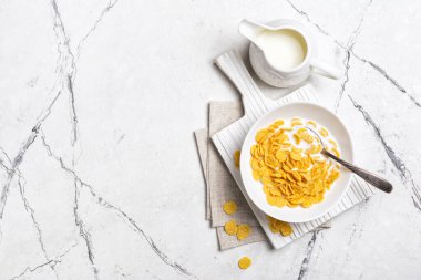 Kahvaltıda mısır gevreği ve sütle birlikte beyaz mermer arka planda fotokopi alanı olan kâse manzarası.