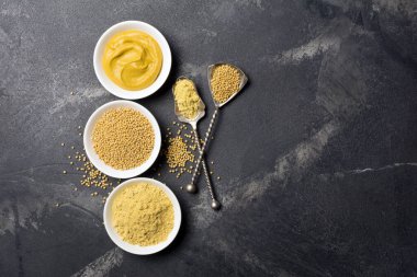 Geleneksel ev yapımı sos ve siyah mermer arka planda siyah kaşık ve fotokopi alanı olan baharatlı yemekler için beyaz kâselere yerleştirilmiş hardal manzarası.