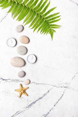 Spa konsepti. Beyaz mermer arka planda gri deniz taşları ve aroma mumlarının üst görüntüsü