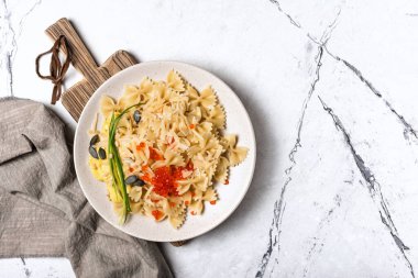 Kırmızı havyar, yeşil soğan, kabak tohumu, çam fıstığı, ahşap tahtadaki sos ve fotokopi alanı olan beyaz mermer arka planlı lezzetli farfalle makarna manzarası.