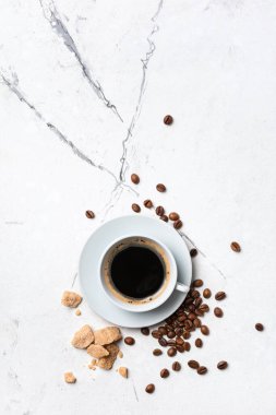 Kahvaltının en üst görüntüsü beyaz fincanda, kamış şekerli, mermer arka planda.
