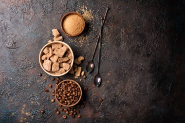 Kahverengi kamış şekerli, şekerli ve granüllü kâselerin üst görüntüsü, lezzetli içecekler için kahve çekirdekleri veya koyu beton arka planda fotokopi alanı olan içecekler.