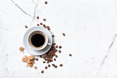 Kahvaltı için kamış şekerli, beyaz bardaktaki sade kahvenin üst görüntüsü mermer zemin üzerinde fotokopi alanı ile.