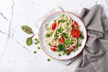 Lezzetli Japon erişteleri, vişneli domatesler, brokoli ve beyaz mermer arka planda yeşil bezelye.