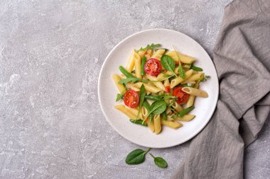Çeri domatesli, yeşil fasulyeli, ıspanaklı ve roka arkaplanlı lezzetli vejetaryen makarna manzarası.