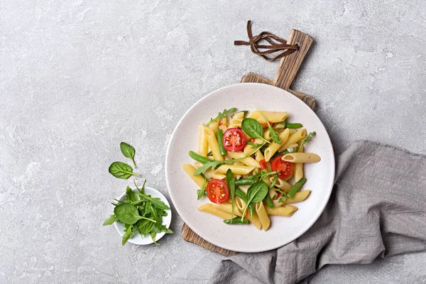 Çeri domatesli, yeşil fasulyeli, ıspanaklı ve roka arkaplanlı lezzetli vejetaryen makarna manzarası.