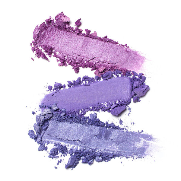 Flat lay of brush strokes. Broken shiny bright purple eyeshadow as samples of cosmetic beauty products isolated on white background