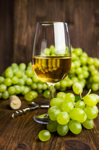 Белое вино в стакане с вином и виноградом
 