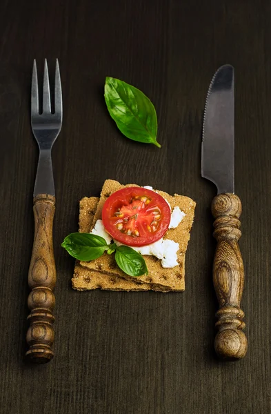 Pain de seigle au fromage, tomates et basilic à la fourchette et au couteau — Photo