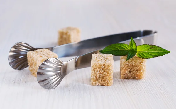 Cane sugar cubes with tongs — Stock Photo, Image