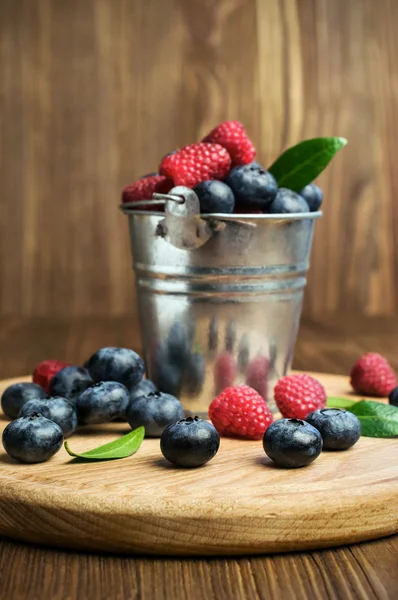 Raspberries and blueberries in a small  bucket — Stock Photo, Image