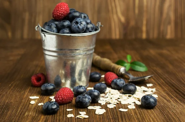 Blueberries , raspberries and oatmeal in a bucket — Stock Photo, Image