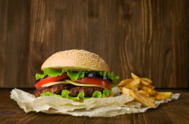 Büyük hamburger ve patates kızartması ahşap arka plan üzerinde