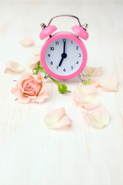 Reloj despertador rosa, rosa y pétalos — Foto de Stock