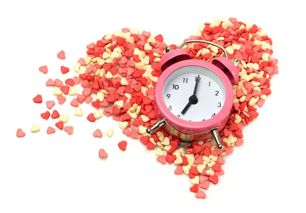 Yağmurlama pembe çalar saat ile kalp şeklinde pasta ve şekerlemeler — Stok fotoğraf