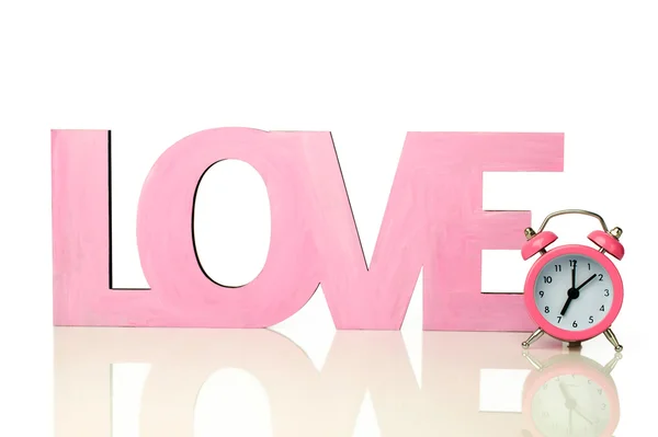 Рожеве слово "любов" з маленьким будильником — стокове фото