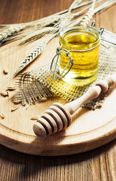 Honey in a glass jar with wooden dipper — Stock Photo, Image
