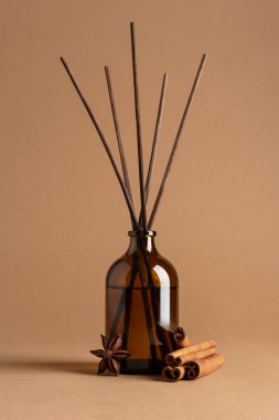 Kahverengi cam kamış yayıcı, aromatik çubuklar, tarçın ruloları ve kahverengi arka planda yıldız anason baharatları. Koku, ev dekorasyonu, sağlık, spa, rahatlama ve doğal yaşam tarzı kavramı..