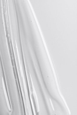 Tarafsız arkaplanda şeffaf kozmetik jel dokusu. Minimum güzellik kavramı berraklığı, saflığı ve modern cilt estetiğini sembolize eder..