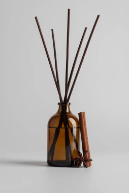 Kahverengi cam kamış yayıcı, aromatik çubuklar, tarçın ruloları ve ışık arka planında yıldız anason baharatları. Koku, ev dekorasyonu, sağlık, spa, rahatlama ve doğal yaşam tarzı kavramı..
