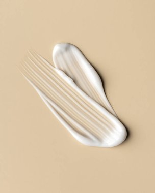 Bej arka planda beyaz kozmetik krem lekesi, makroda yakalanmış. Düz parlak doku cilt bakımı, güzellik ürünleri, nemlendirici reklamlar, şablonlar ve temiz minimalist tasarımlar için idealdir..