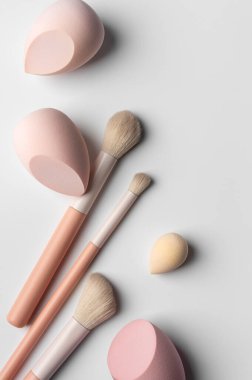 Minimalist makyaj fırçaları ve süngerler temiz ve nötr bir arka plana yerleştirilmiş. Profesyonel güzellik araçları, hassasiyet, yumuşak uygulama, cilt rutini ve modern temiz estetik kavramı.