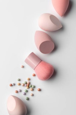 Pastel makyaj süngerleri ve temiz bir arka planda renkli kozmetik allık inci ile yumuşak toz fırçası. Cilt bakımı, makyaj, kozmetik ve kendine bakım temaları için minimum güzellik kompozisyonu