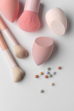 Pastel makyaj süngerleri ve temiz bir arka planda renkli kozmetik allık inci ile yumuşak toz fırçası. Cilt bakımı, makyaj, kozmetik ve kendine bakım temaları için minimum güzellik kompozisyonu