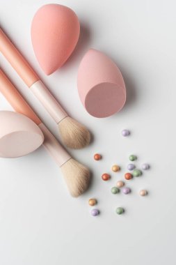 Pastel makyaj süngerleri ve temiz bir arka planda renkli kozmetik allık inci ile yumuşak toz fırçası. Cilt bakımı, makyaj, kozmetik ve kendine bakım temaları için minimum güzellik kompozisyonu