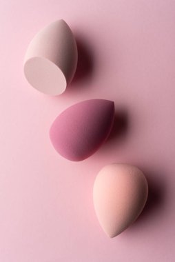 Pembe arka planda Pastel makyaj süngerleri. Yumuşak dokuları ve yumuşak renkleri olan minimal güzellik aletleri, cilt bakımı, kozmetik ürünleri ve modern güzellik markalaşması için ideal..