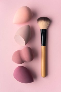 Pembe arka planda, yumuşak süngerleri ve fırçası olan minimum makyaj aletleri. Temiz, kadınsı güzellik konsepti yumuşak cilt bakımına, sakin rutine, modern estetiğe ve pastel tonlara odaklandı..