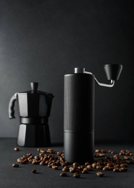 Moka pot, el değirmeni ve kızarmış fasulye ile elle kahve demleme seti. Dramatik ışıklandırma, minimalizm, işçilik, odaklanma ve lüks yaşam tarzı içeren kaliteli kahve ritüeli kavramı.