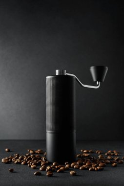 Koyu arkaplanda kızarmış fasulye ile elle kahve öğütücü. Dramatik ışıklandırma, minimalizm, işçilik, odaklanma ve lüks yaşam tarzı içeren kaliteli kahve ritüeli kavramı.